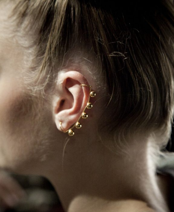 Chica con un piercing en la oreja con varias perlas doradas