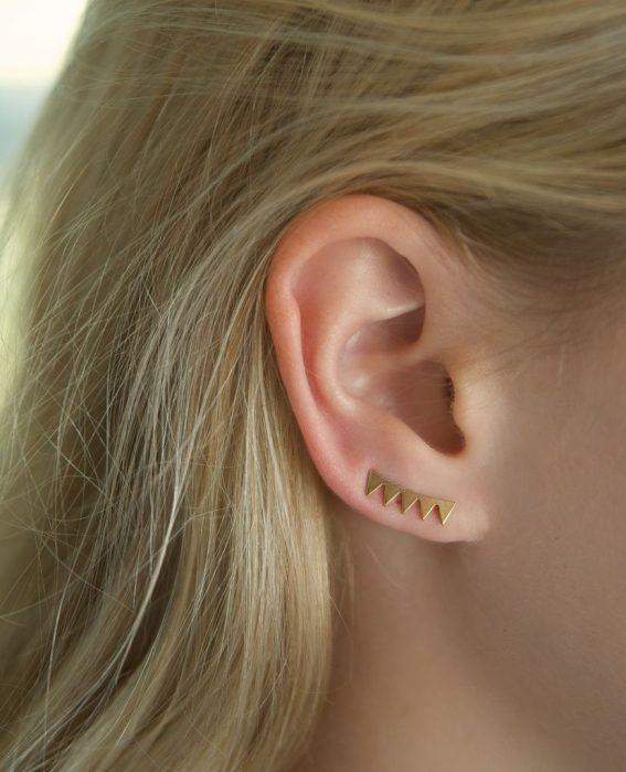 Chica con un piercing en la oreja con forma de flechas