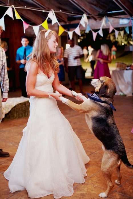 mujer rubia con vestido de novia bailando con perro 