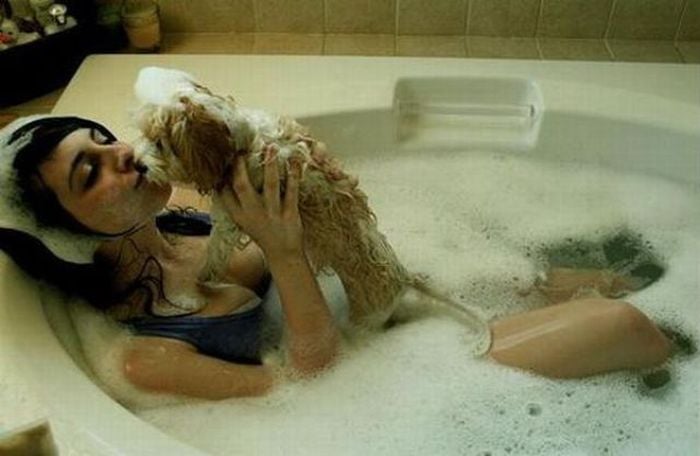 Chica tomando un baño de espuma junto a su perro 