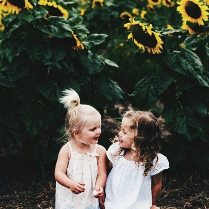 niña rubia le toma la mano a niña de cabello castaño 