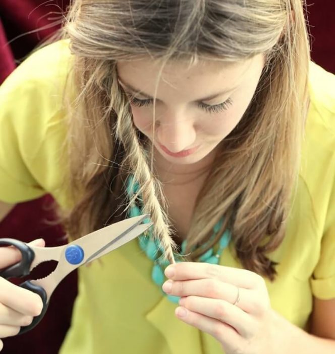 mujer rubia enrollandose el cabello y recortando sus puntas 