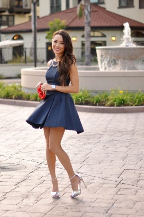 Chica usando un vestido azul y tacones en colo plateado mientras posa para una fotografía 