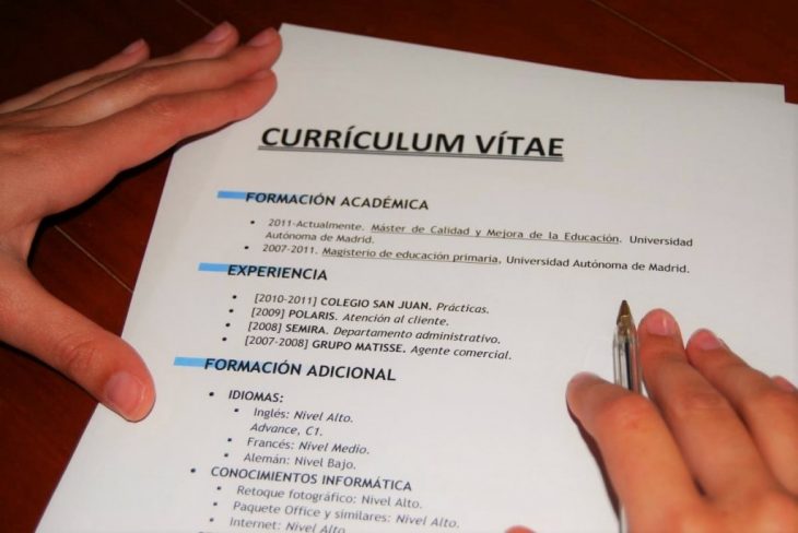 hoja con curriculum vitae y manos con pluma 