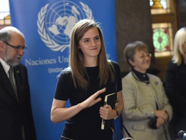 mujer rubia con libro en mano sonriendo saluda 