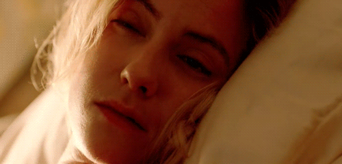 mujer rubia acostada en la cama con despertador
