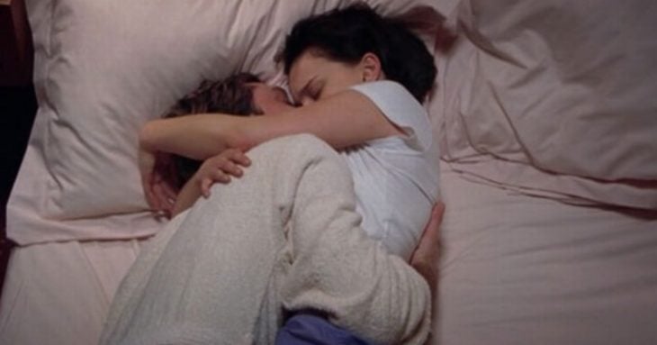 pareja acostada en la cama abrazada y besándose 