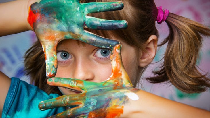 niña con manos pintadas de colores y ojos azules 
