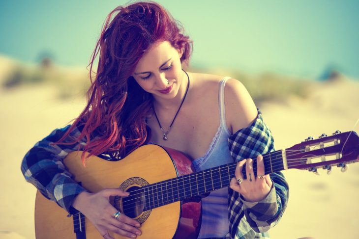 mujer pelirroja con guitarra y camisa de cuadros 