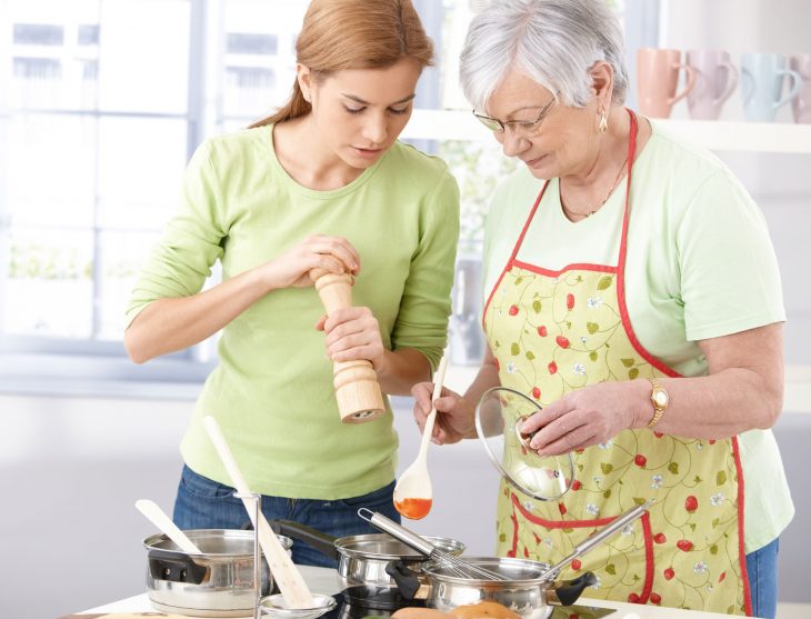 Abuela enseñando a cocinar a su nieta. 