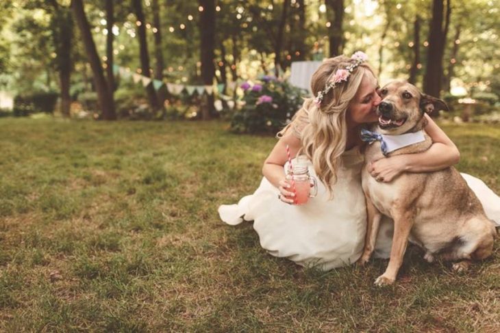 novia con vestido blanco besando y abrazando a perro 