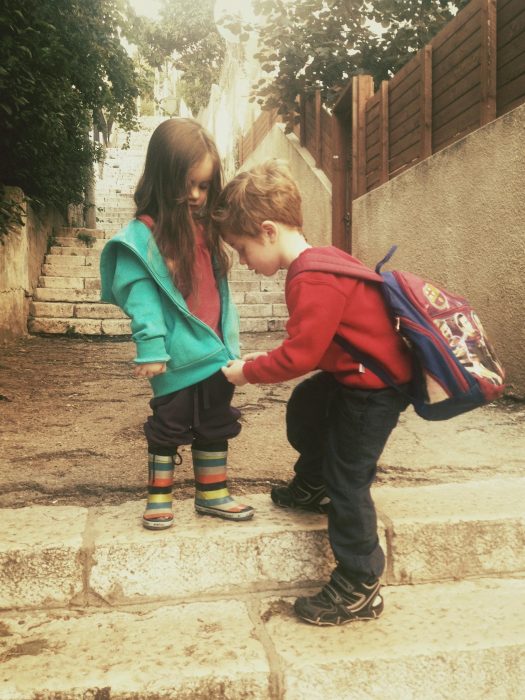 Niño abrochandole el suéter a su hermana. 