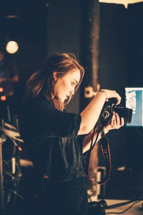 mujer rubia con camara tomando fotos en oscuridad 