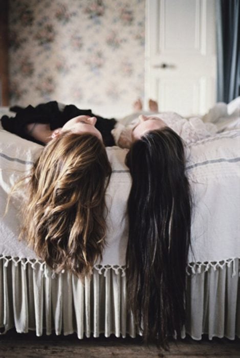 Chicas acostadas en la cama platicando 