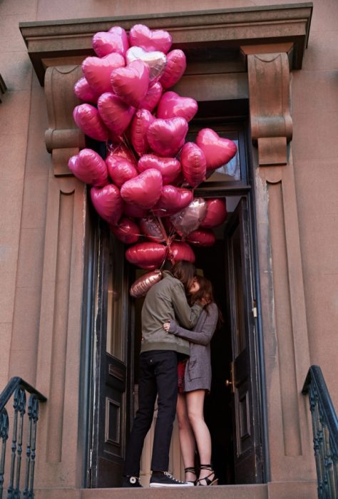 Chico regalandole globos de corazones a su novia 