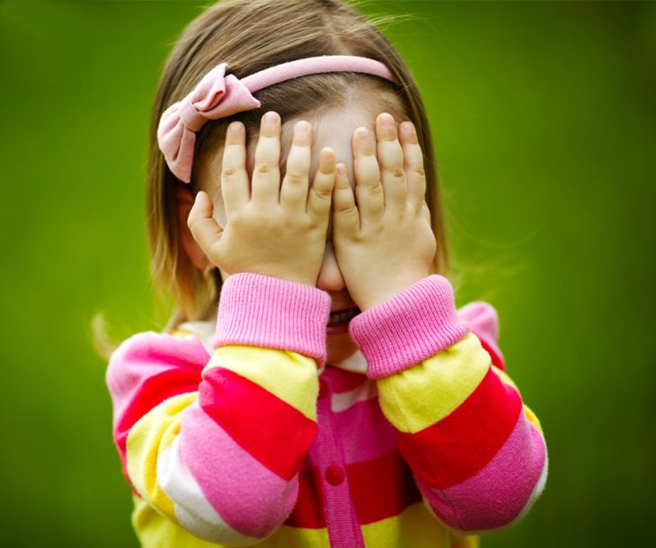 niña con sueter de rayas y manos en su cara 