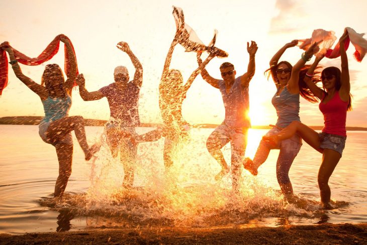 Grupo de personas brincando en la playa. 