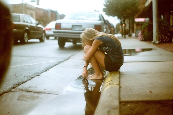 mujer rubia sentada en la banqueta sin pies 