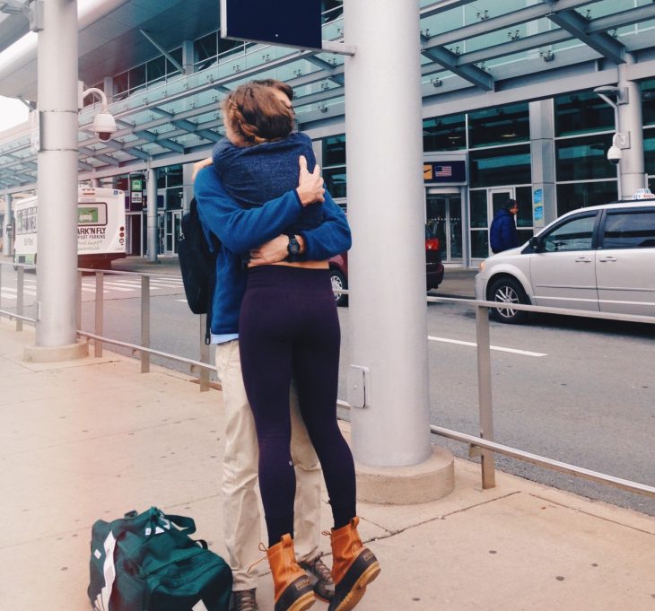 pareja abrazándose afuera de un aeropuerto 