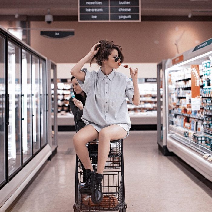 mujer con camisa y cabello agarrado con lentes sobre carro de supermercado 