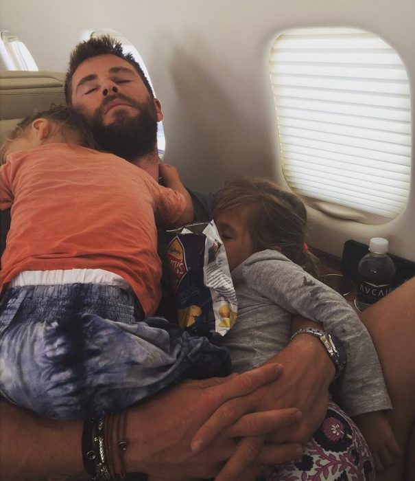 hombre en asiento de avion con dos niños dormidos 