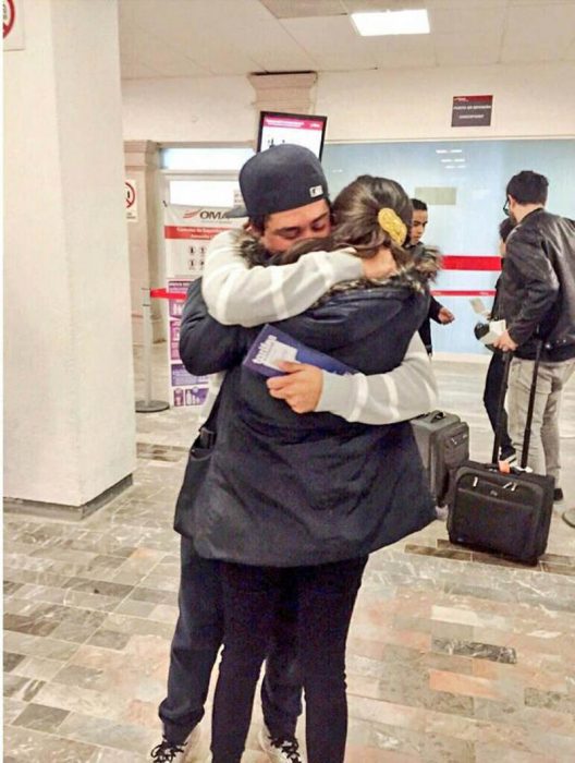 pareja abrazada con gorra en aeropuerto 