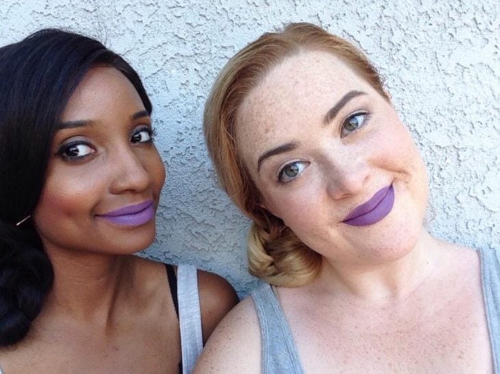 Dos mujeres de piel blanca y morena con labial purpura 