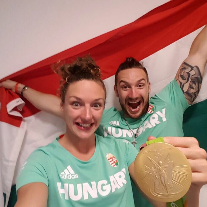 hombre y mujer con camisa verde, medalla de oro y bandera 