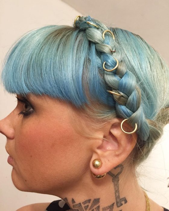 mujer rubia con cabello azul, fleco y anillos 