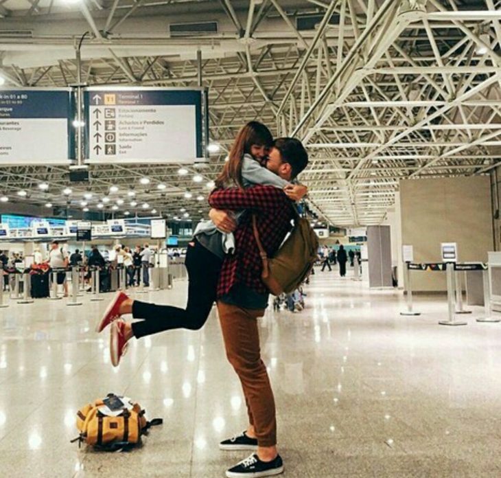 pareja abrazada con gorra en aeropuerto 