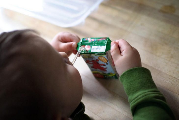 niño tomando jugo de cajita