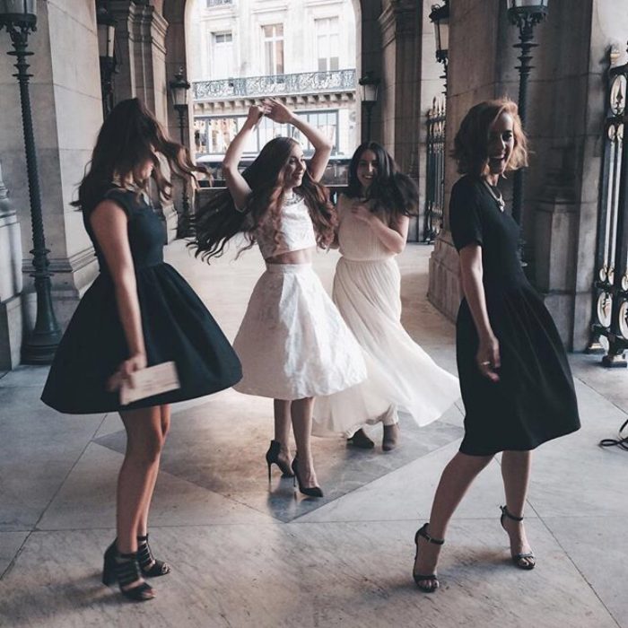 mujer con vestido blanco bailando con otras mujeres 