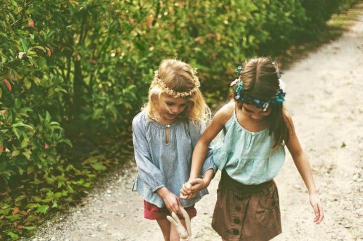 niñas con flores en la cabeza tomadas de la mano