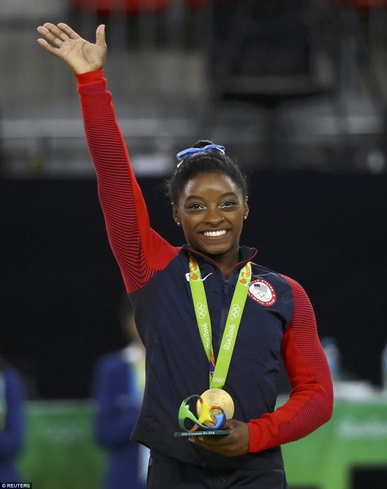 mujer morena con medalla levanta la mano 