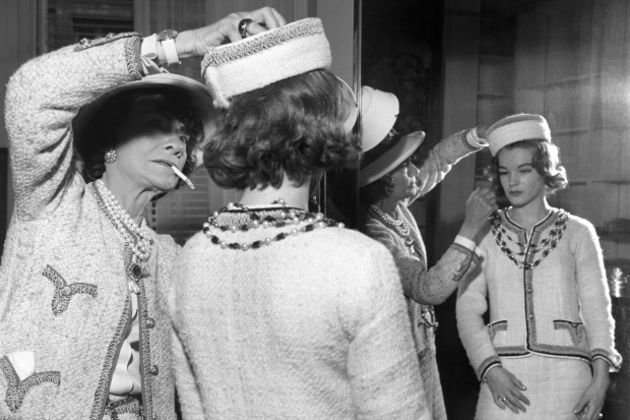 mujer con sombrero arreglando sombrero de mujer frente al espejo 