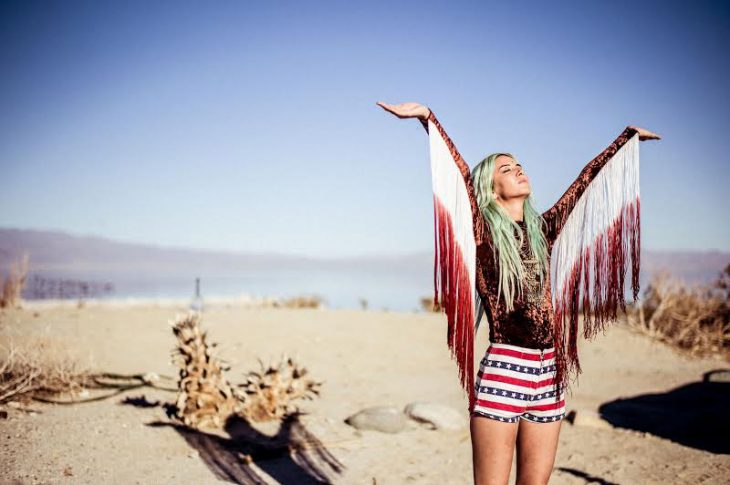 Chica en n desierto levantando las manos hacia el cielo 