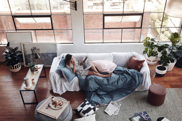 Chica sentada en un sofá leyendo el periódico 