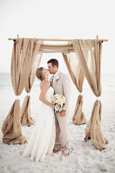 Pareja besándose el día de su boda en la playa