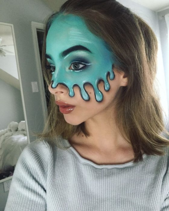 Chica crea maquillaje de fantasía de una gran mancha azul corriendo por su rostro 