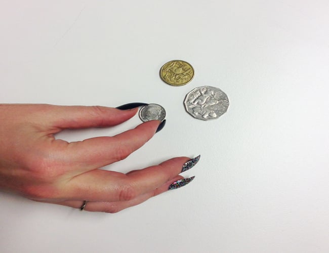 Chica intentando levantar las monedas de una superficie plana 