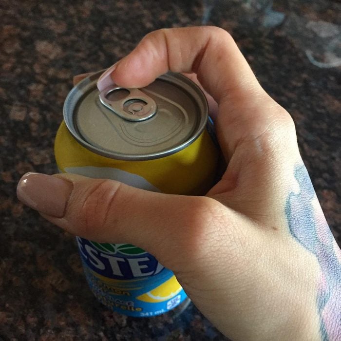 Chica con uñas postizas tratando de abrir una lata 