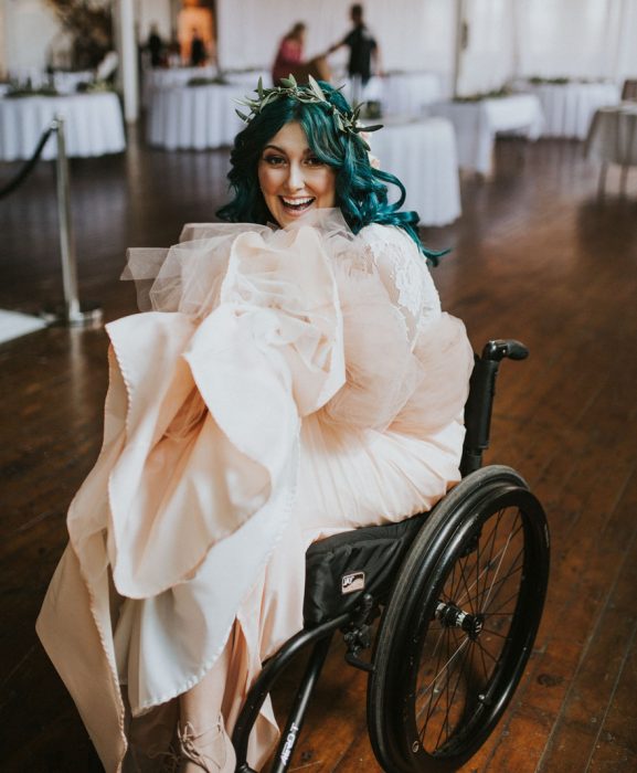 Chica en silla de ruedas mostrando su vestido el día de su boda