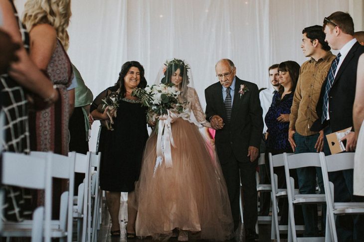 Madre y abuelo de una novia caminando junto a ella el día de su boda 