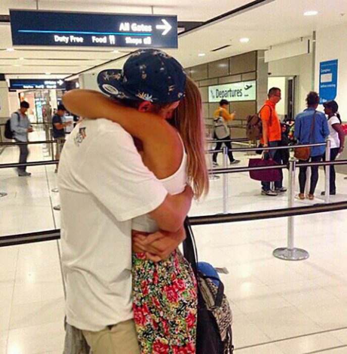 pareja abrazada con gorra en aeropuerto 