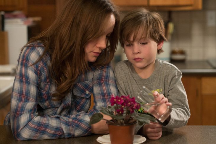 mujer blanca cabello castaño alimentando planta con niño 