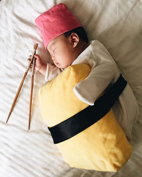 Bebé recostada en la cama disfrazada de sushi