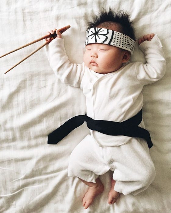 Bebé recostada en la cama disfrazada de Karate Kid