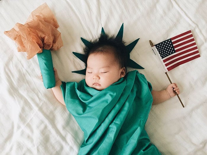 Bebé recostada en la cama disfrazada de estatua de la libertad