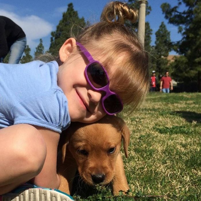 niña con lentes abrazando a un perro