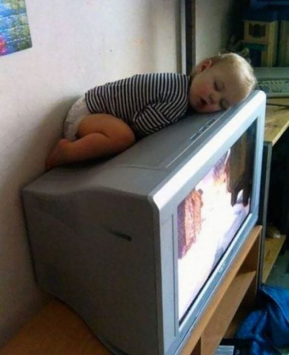 Niño durmiendo sobre la parte de arriba de una televisión 